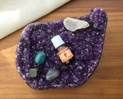 Grapefruit essential oil bottle on a raw amethyst crystal